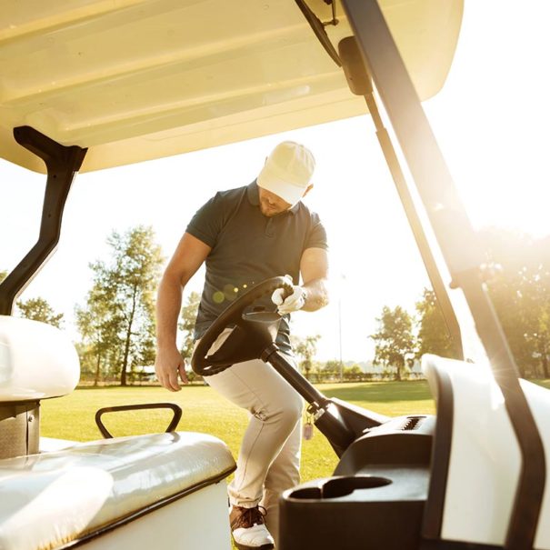 Young male golfer getting in a golf cart