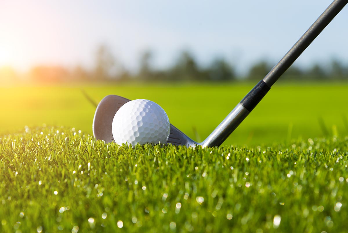 Golf club and ball in grass and sunset