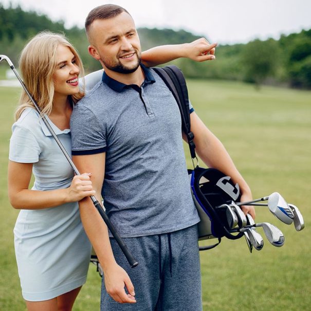 Couple in a golf course. Blonde in a sport clothes. Pair playing golf